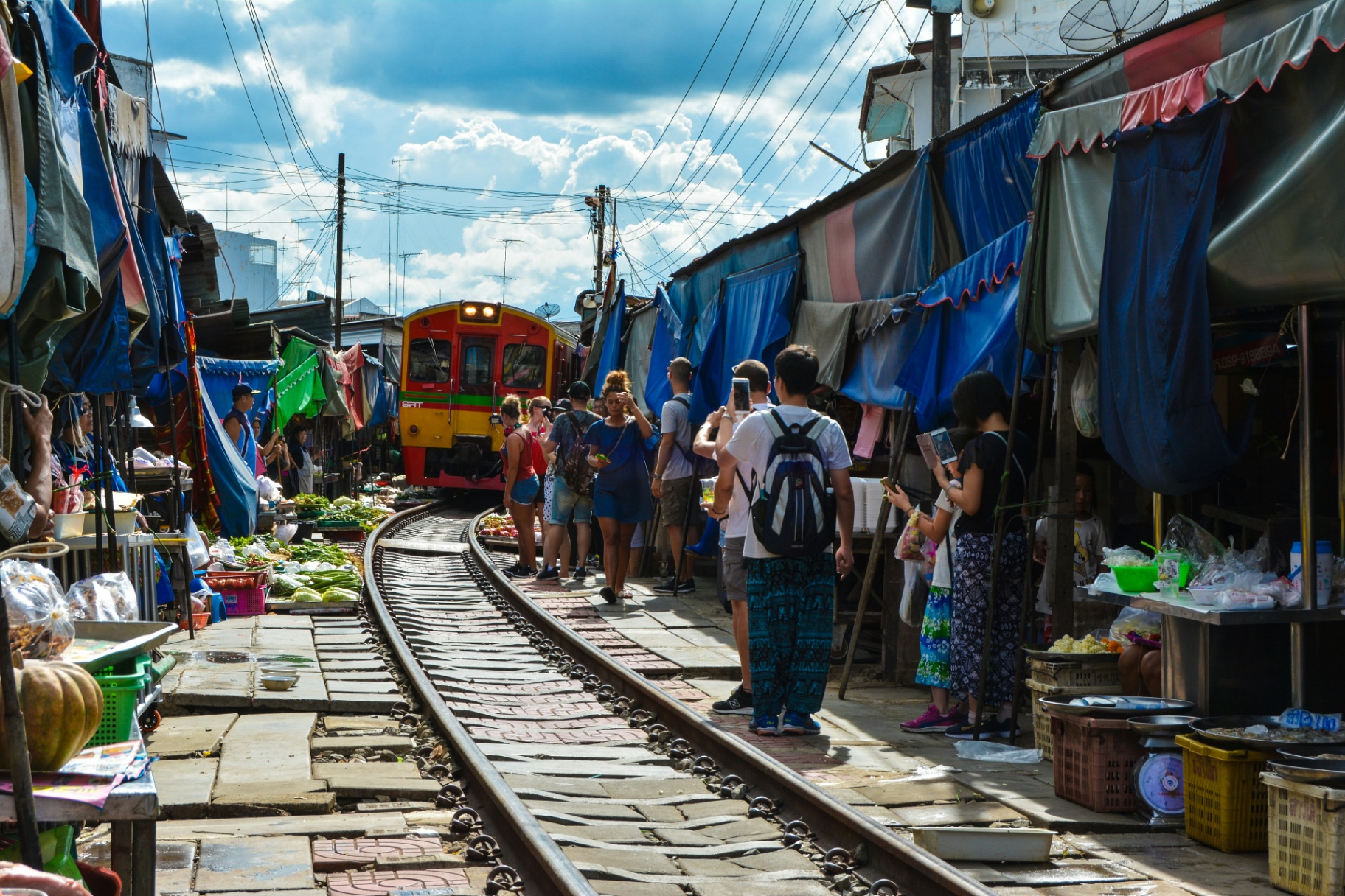 Busy railway market in Asia with a train passing through colourful stalls